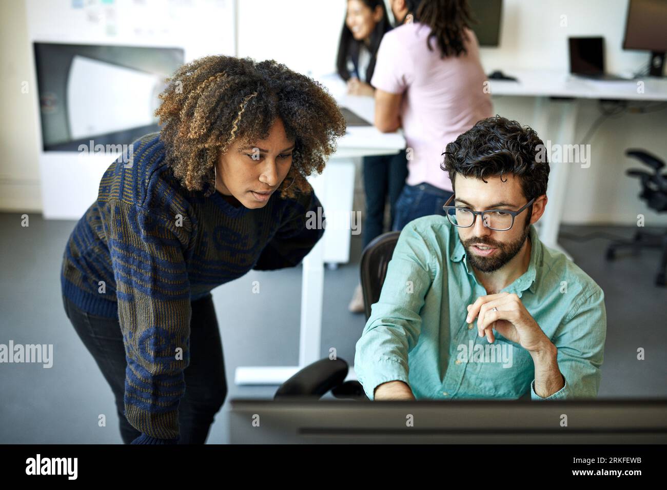 Vue à angle élevé de l'homme d'affaires confiant expliquant à la femme d'affaires sur l'ordinateur de bureau dans le bureau Banque D'Images