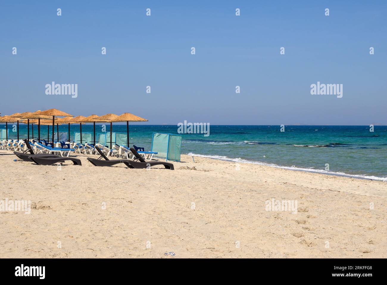 Transats avec parasol sur la plage de sable de Marmari. L'île grecque de Kos Banque D'Images