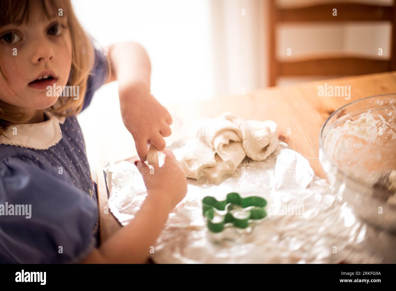 jeune fille faisant des biscuits de noël portant une robe smockée Banque D'Images