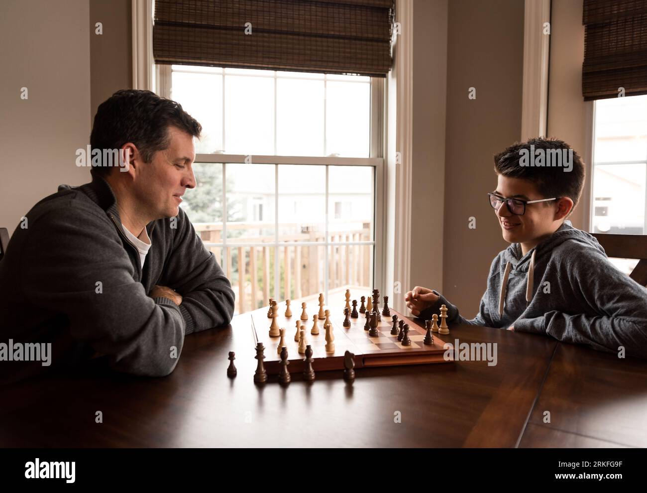 Père et fils riant en jouant aux échecs ensemble à la table. Banque D'Images