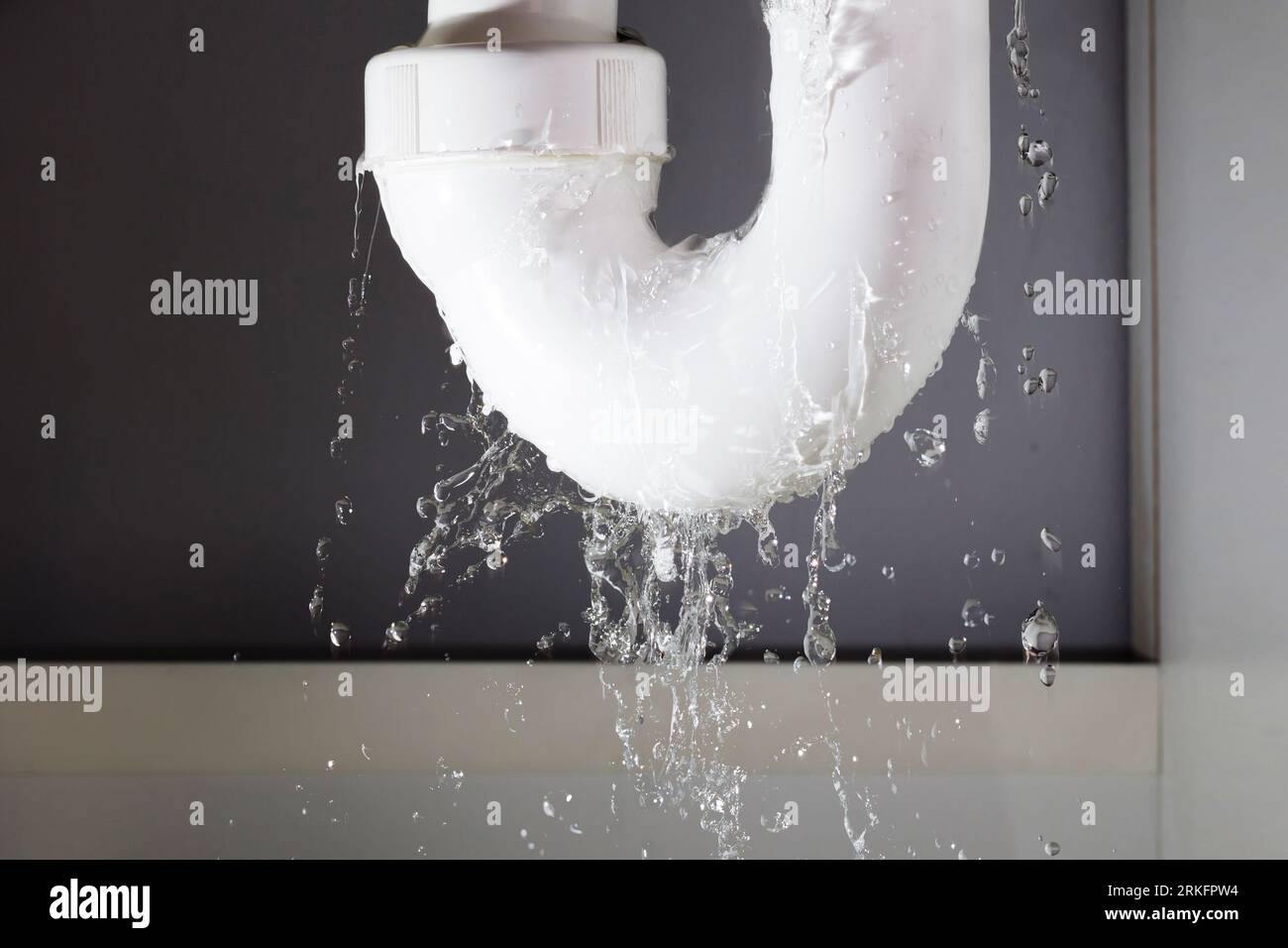 Les fuites d'eau à partir de la canalisation en acier inoxydable sur fond gris Banque D'Images