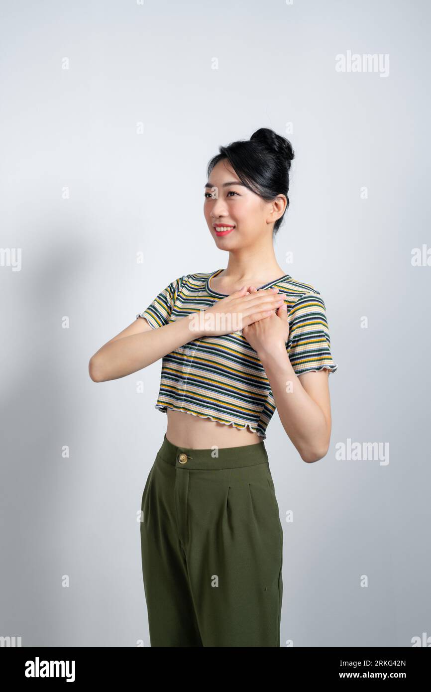 Portrait de jeune femme touchée se sentant flattée, tenant les mains sur le cœur et souriant, dites merci Banque D'Images