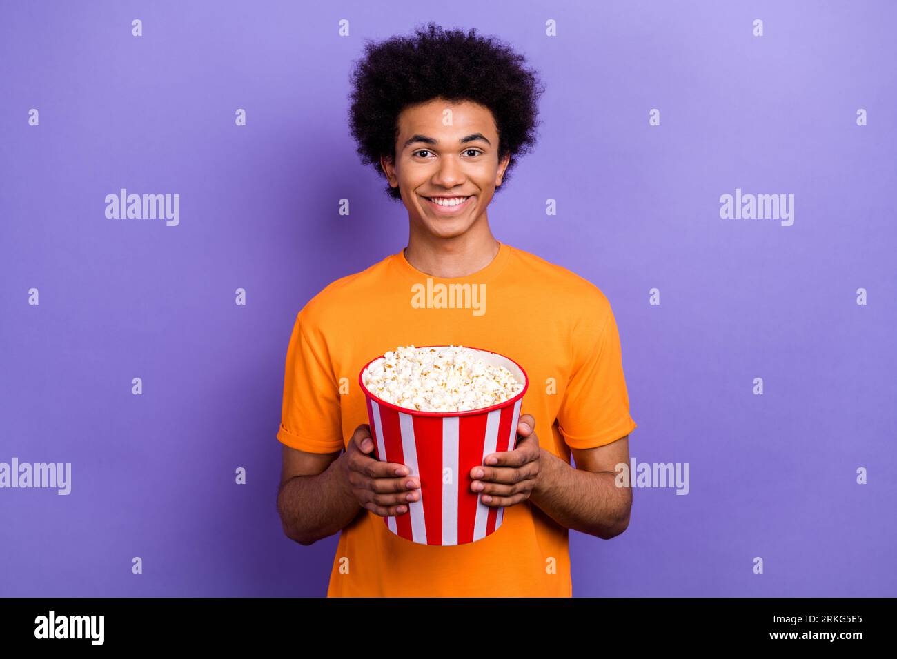 Photo de portrait de jeune gars joyeux attendant sa petite amie manger pop corn seau regarder film 3d isolé sur fond de couleur violette Banque D'Images