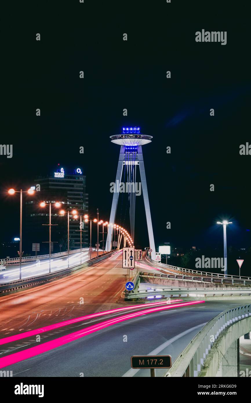 Une grande structure s'étend sur un plan d'eau, avec deux rangées de lumières vives de chaque côté Banque D'Images