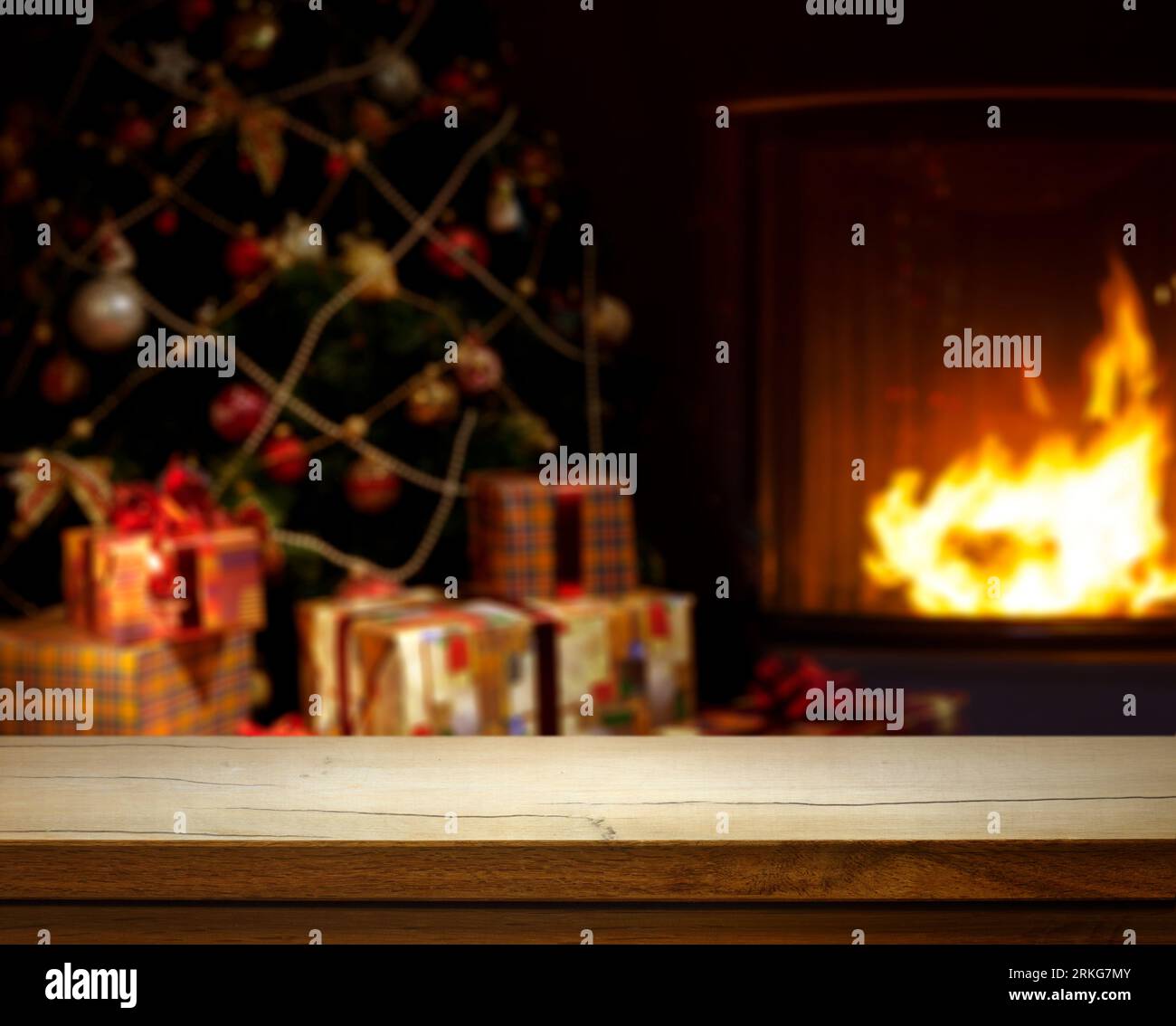 Table en bois vide sur fond de Noël défoqué avec arbre de Noël, cadeaux et cheminée ; espace libre pour votre décoration. Banque D'Images