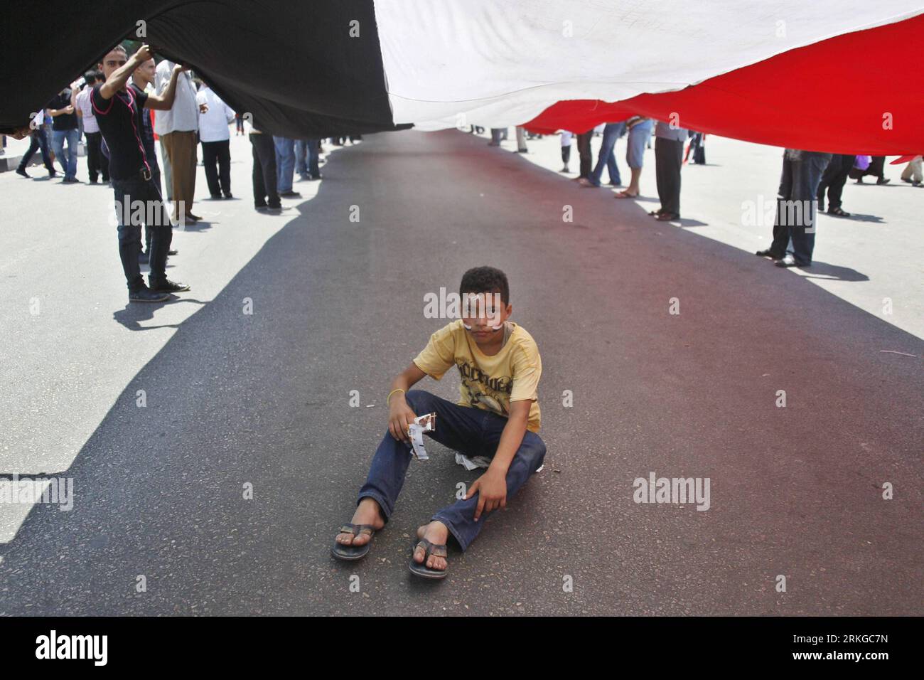 Bildnummer : 55579750 Datum : 08.07.2011 Copyright : imago/Xinhua (110708)-- LE CAIRE, 8 juillet 2011 (Xinhua) -- Un garçon assis sous un drapeau géant lors d'une manifestation de masse organisée sur la place Tahrir, le Caire, Egypte, le 8 juillet 2011. Des milliers d'Égyptiens ont afflué sur la place Tahrir du centre du Caire dans ce qu'ils ont appelé le Premier vendredi de la Révolution, appelant l'armée au pouvoir à satisfaire toutes les exigences de la Révolution du 25 janvier. Ils ont également appelé à purifier et à restructurer les institutions policières, et à accélérer les procès de tous les anciens responsables du régime et policiers impliqués dans le meurtre de manifestants et dans le chaos. Banque D'Images