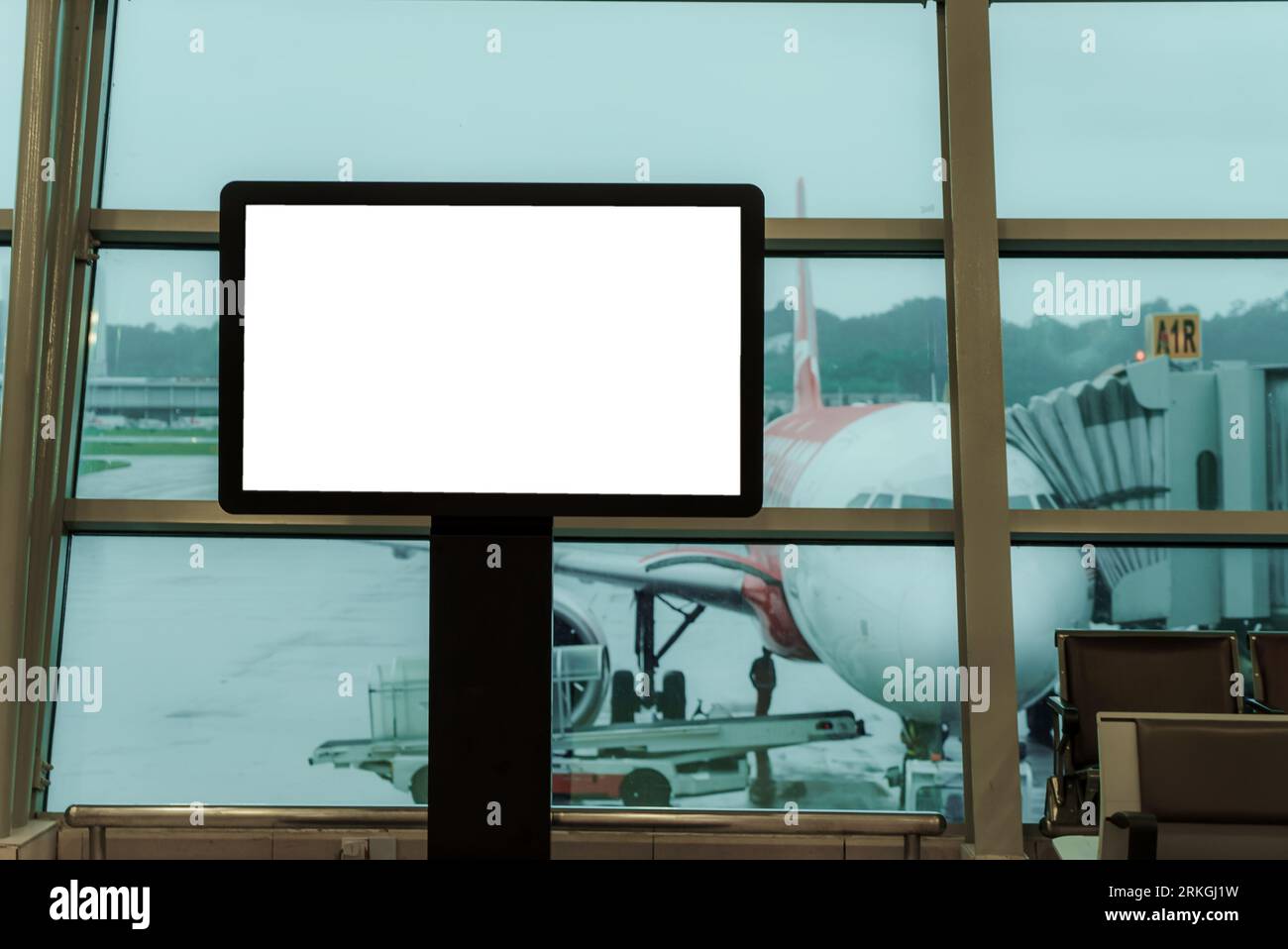 Un panneau d'affichage vide à l'aéroport, accompagné de sièges, présente un arrière-plan d'avion subtil, offrant un espace privilégié pour mettre en valeur votre message. Banque D'Images