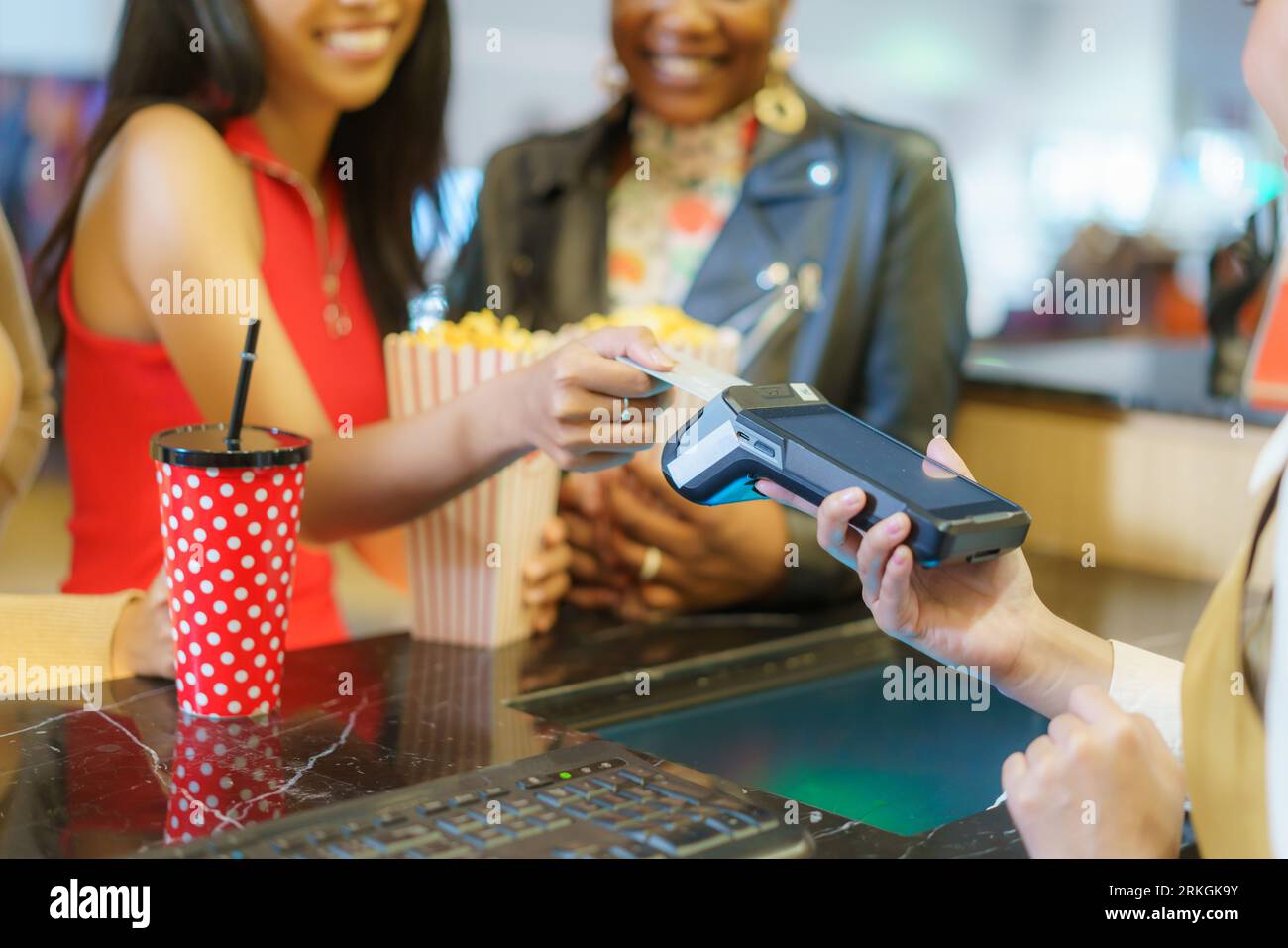 couple de lesbiennes femmes paie pour les billets de cinéma au comptoir, en utilisant leur carte de crédit, ajoutant la commodité moderne à leur sortie de cinéma. Banque D'Images