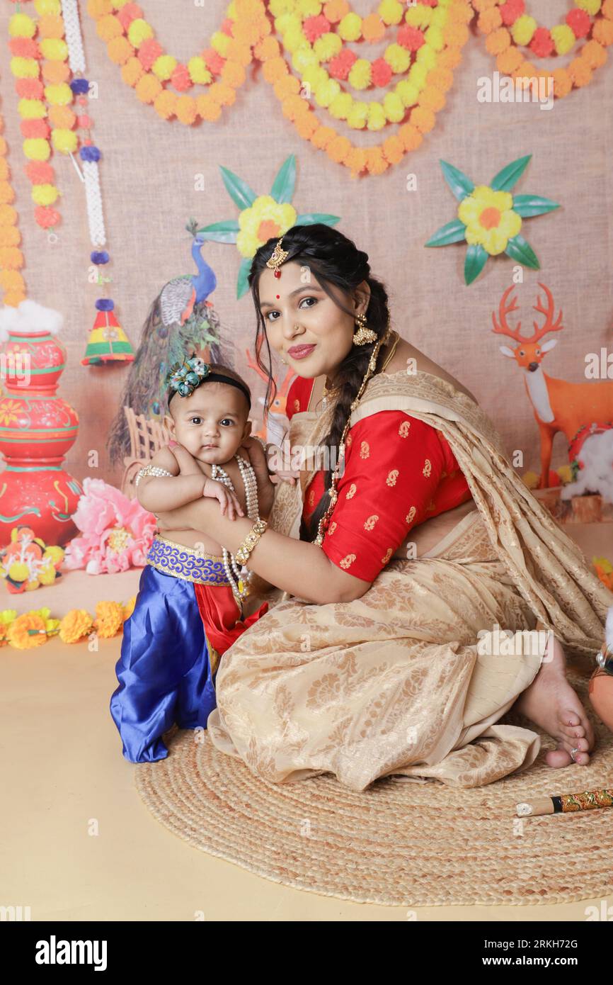 Janmashtami concept. Mère assise avec son mignon petit garçon déguisé en petit krishna. Banque D'Images