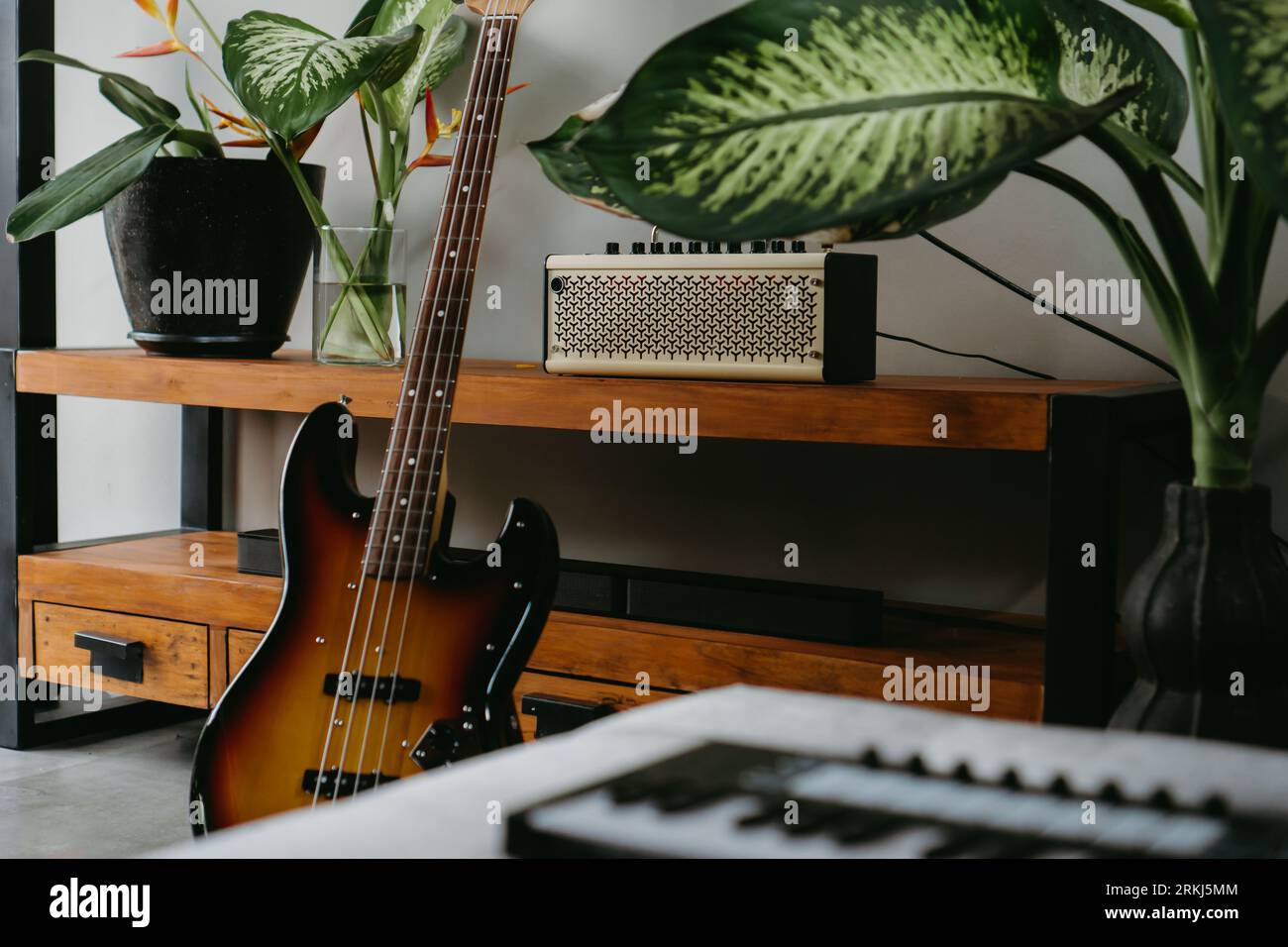 Un mixeur de musique professionnel sur une table en bois dans une pièce confortable, avec une guitare électrique en arrière-plan offrant une atmosphère créative Banque D'Images