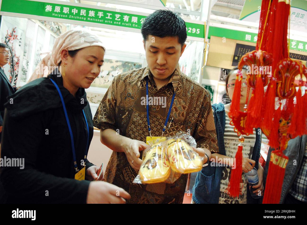 Bildnummer : 56084374 Datum : 23.09.2011 Copyright : imago/XINHUA (110923) -- YINCHUAN, 23 septembre 2011 (Xinhua) -- Yuan Surya (R) sélection de produits chinois pour ses enfants à un stand d'exposition en 2011 China (Yinchuan) Investment and Trade Fair, à Yinchuan, capitale de la région autonome de Ningxia hui au nord-ouest de la Chine, le 23 septembre 2011. Yuan Surya, un marchand indonésien qui vend de la nourriture islamique, a participé pour la première fois à la Foire de l'investissement et du commerce chinois de 2011 à Yinchuan. En plus de négocier avec les clients et les partenaires et de vendre ses produits, il a également profité de cette occasion pour Banque D'Images