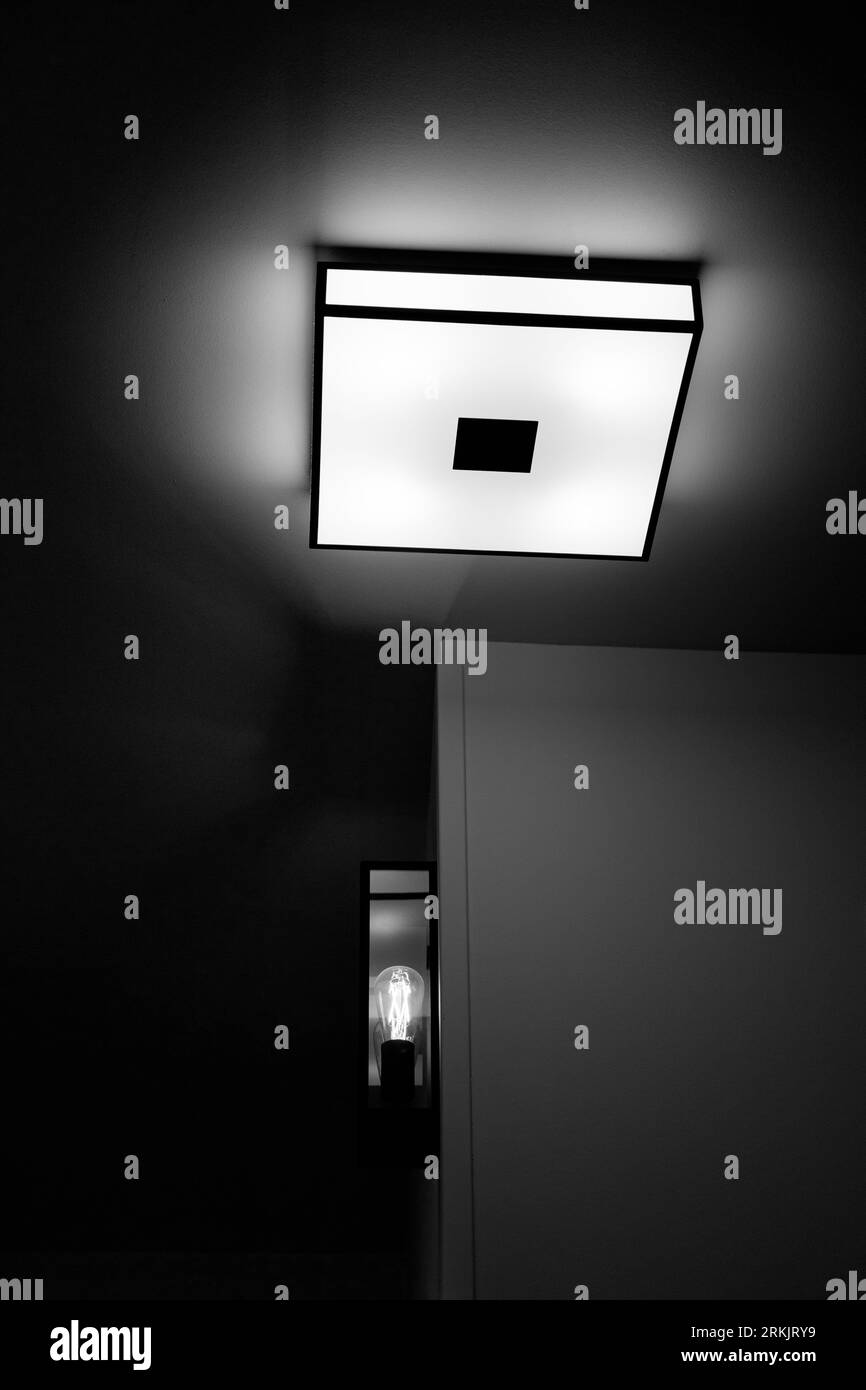 image en noir et blanc regardant un luminaire au plafond et au mur dans une chambre d'hôtel. Banque D'Images