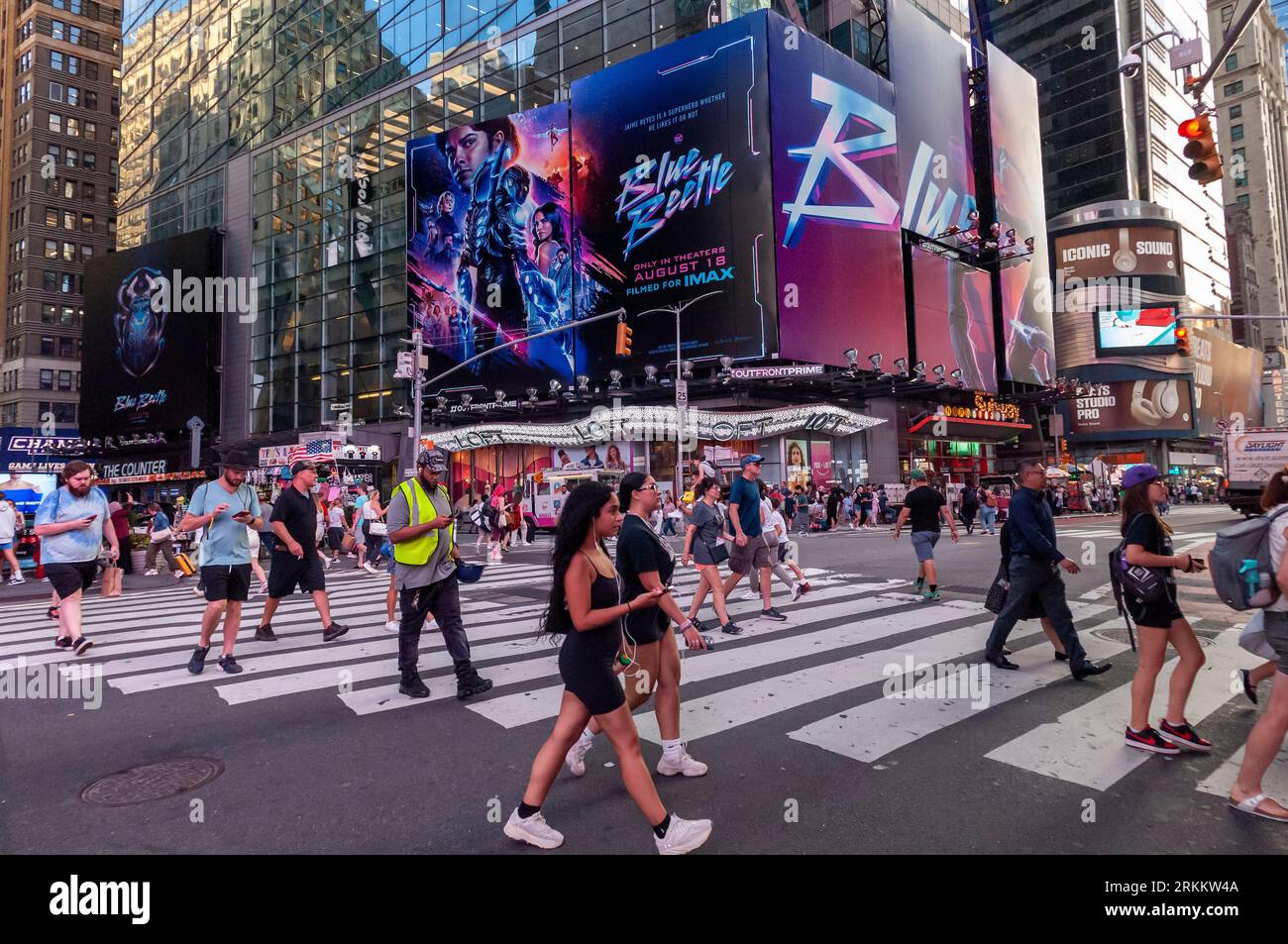 Des hordes de gens traversent West 42nd Street sous la publicité pour Warner Bros. PicturesÕ ÒBlue BeetleÓ film à Times Square à New York le vendredi 18 août 2023. Au cours de son week-end de sortie, ÒBlue BeetleÓ a supplanté ÒBarbieÓ en tant que film le plus rentable avec un montant estimé à 25,4 millions de dollars. . (© Richard B. Levine) Banque D'Images