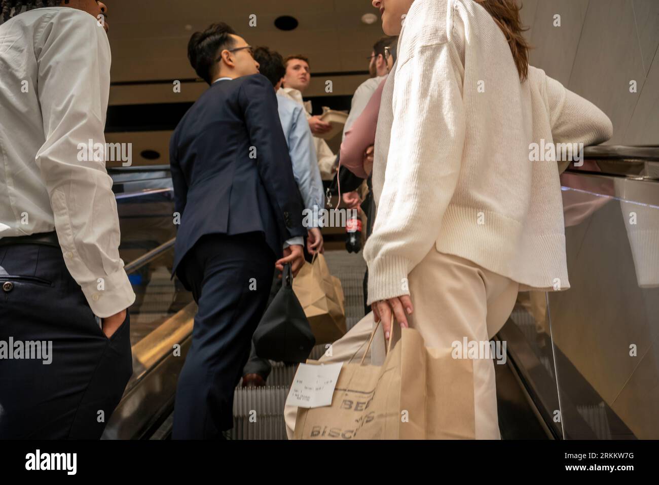 Groupe d'employés de bureau avec leurs repas à emporter après avoir visité la salle de restauration sur un escalator dans le Moynihan train Hall à New York le mardi 22 août 2023. (© Richard B. Levine) Banque D'Images