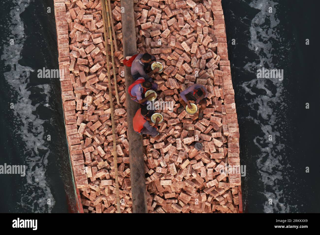 DHAKA, BANGLADESH-25 FÉVRIER 2021 : les ouvriers prennent leur petit déjeuner sur un bateau chargé de voiles en briques sur la rivière Dhaleshwari à Keraniganj, dans la banlieue de Dhaka, Bangladesh, le 25 février 2021. Banque D'Images