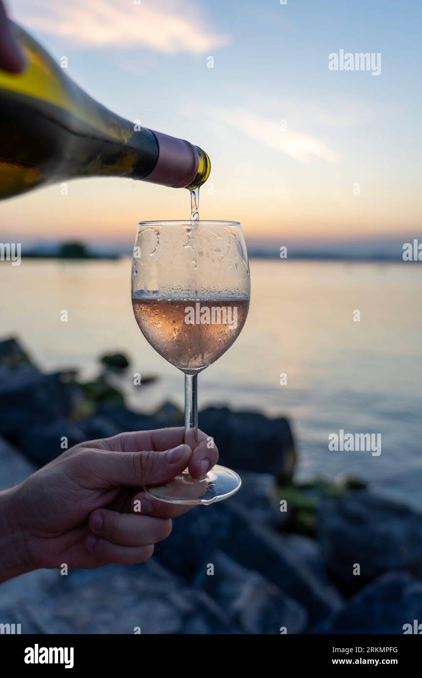 Versez le vin dans un verre d'une bouteille sur un pique-nique à côté du lac Balaton . Banque D'Images
