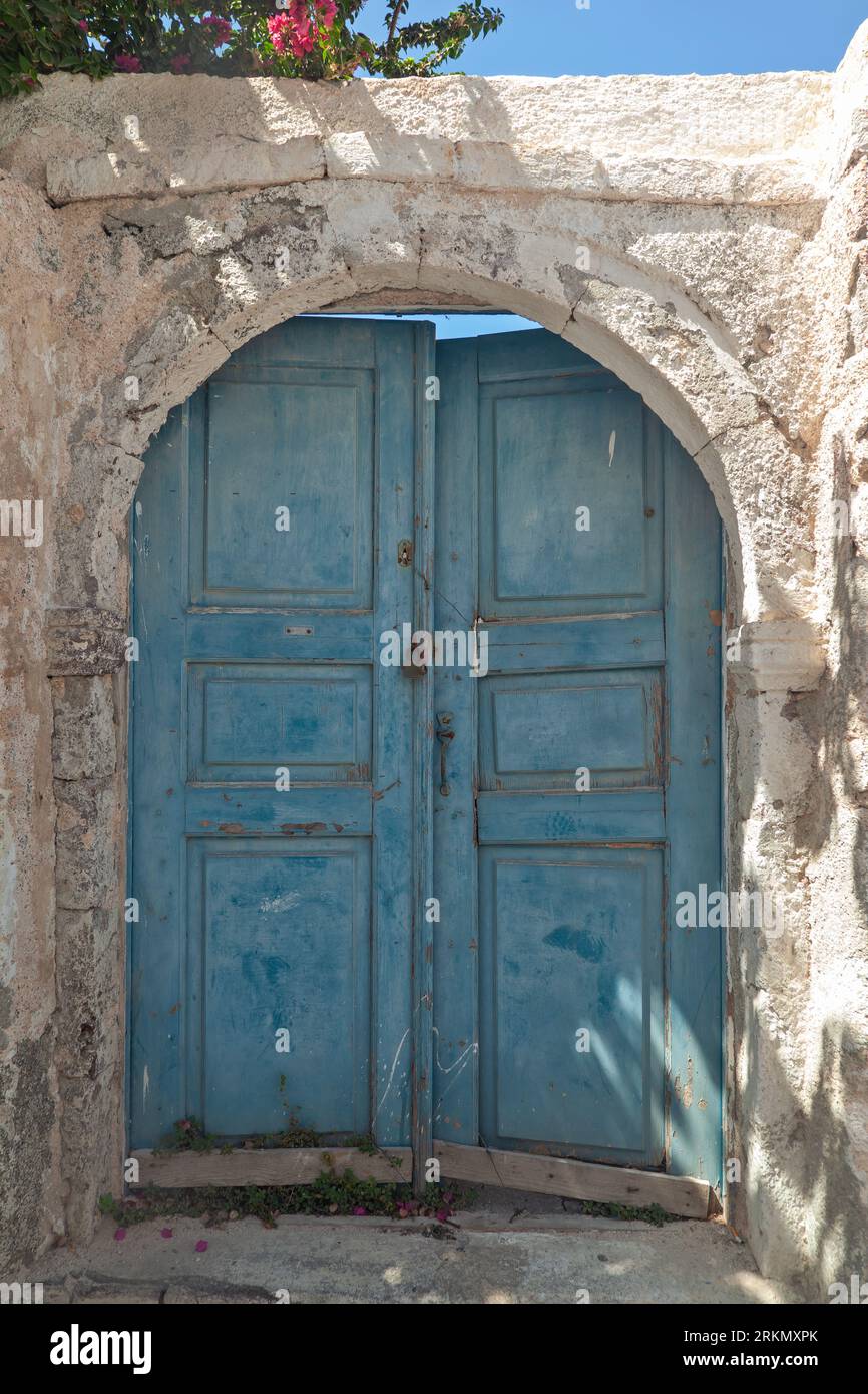 Vieille porte traditionnelle en bois de couleur bleu clair dans une vieille maison avec des murs ocre et seuil de pierre, dans le village Oia de Santorin, Grèce. Banque D'Images