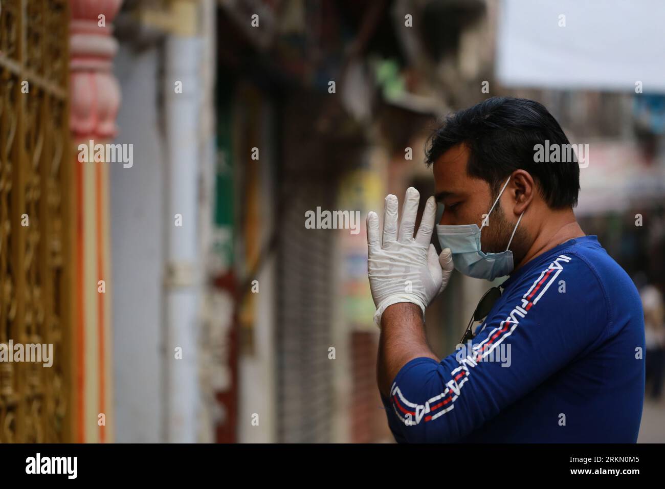 DHAKA, BANGLADESH - 31 MARS 2020 : un dévot hindou porte un masque facial et des gants pour prier devant un temple pendant le confinement national en tant que mesure préventive contre l’épidémie de coronavirus COVID-19, à Dhaka, Bangladesh, le 31 mars 2020. Banque D'Images