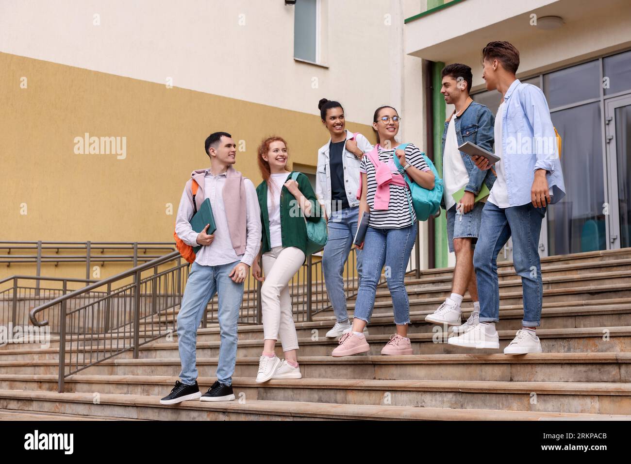 Groupe de jeunes étudiants heureux marchant dans les escaliers à l'extérieur Banque D'Images