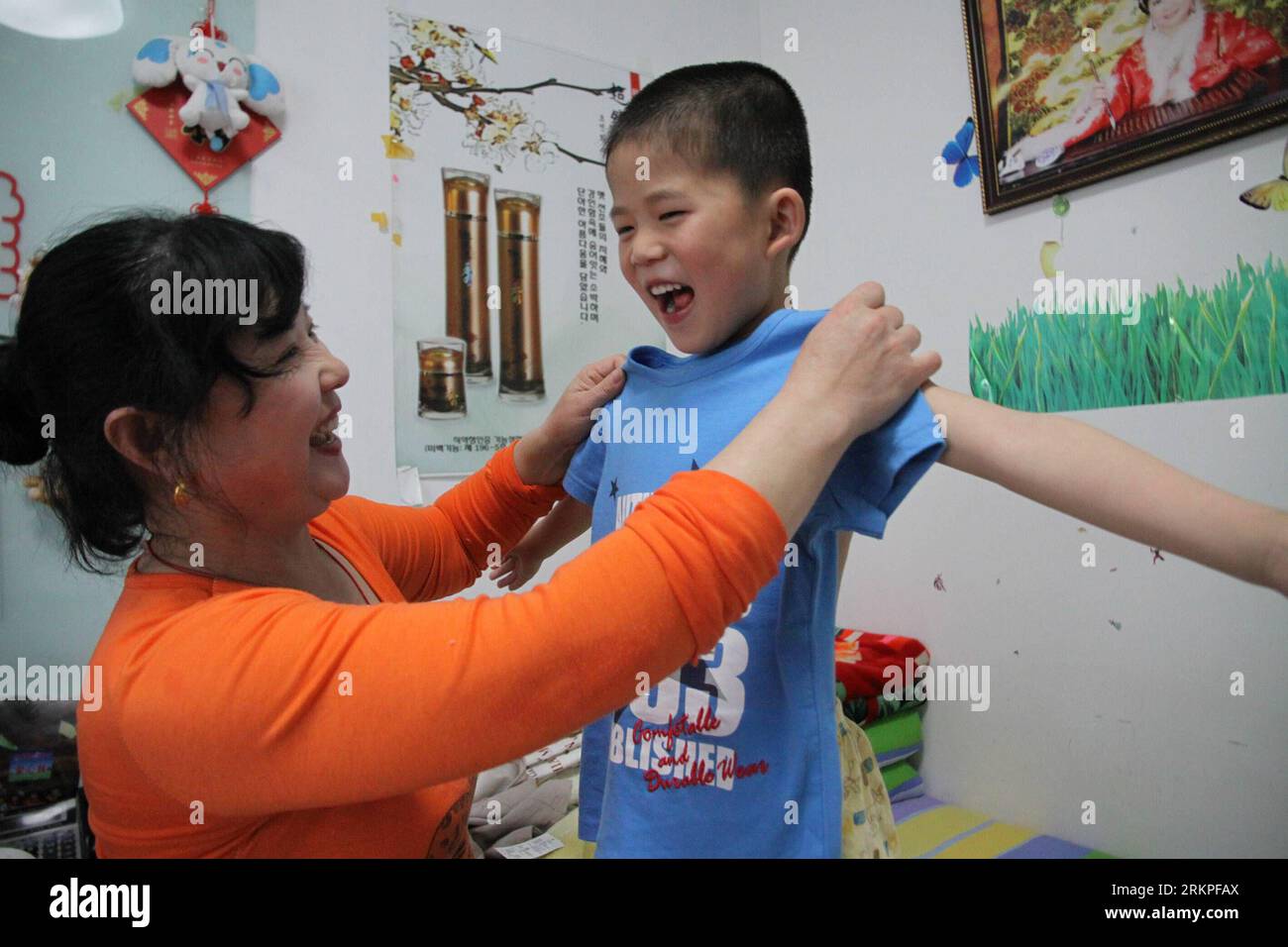 Bildnummer : 57982286 Datum : 11.05.2012 Copyright : imago/Xinhua (120512) -- WEIHAI, 12 mai 2012 (Xinhua) -- Liu Anni aide Meng Jiale à porter un nouveau T-shirt à la maison à Weihai, dans la province du Shandong de l'est de la Chine, le 11 mai 2012, deux jours avant la fête des mères. Il y a plusieurs citoyens à Weihai qui prennent soin des enfants dans les maisons de protection sociale et ramènent souvent les enfants à la maison et les laissent ressentir l'amour des mères. (Xinhua/Yu Qibo) (zhs) CHINE-SHANDONG-MAISON DE PROTECTION SOCIALE-ENFANTS (CN) PUBLICATIONxNOTxINxCHN Gesellschaft Erziehung Tagesmutter Betreuung Kinderbetreuung xrj x0x 2012 quer 57982286 Banque D'Images