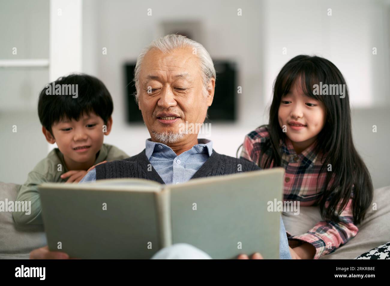 grand-père asiatique senior ayant un bon moment avec deux petits-enfants à la maison Banque D'Images