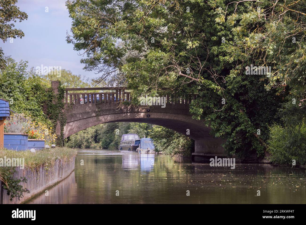 Deux petits bateaux attachés à la rive de la rivière Stort juste après un vieux pont près de Halow Angleterre avec un ciel bleu clair en arrière-plan Banque D'Images