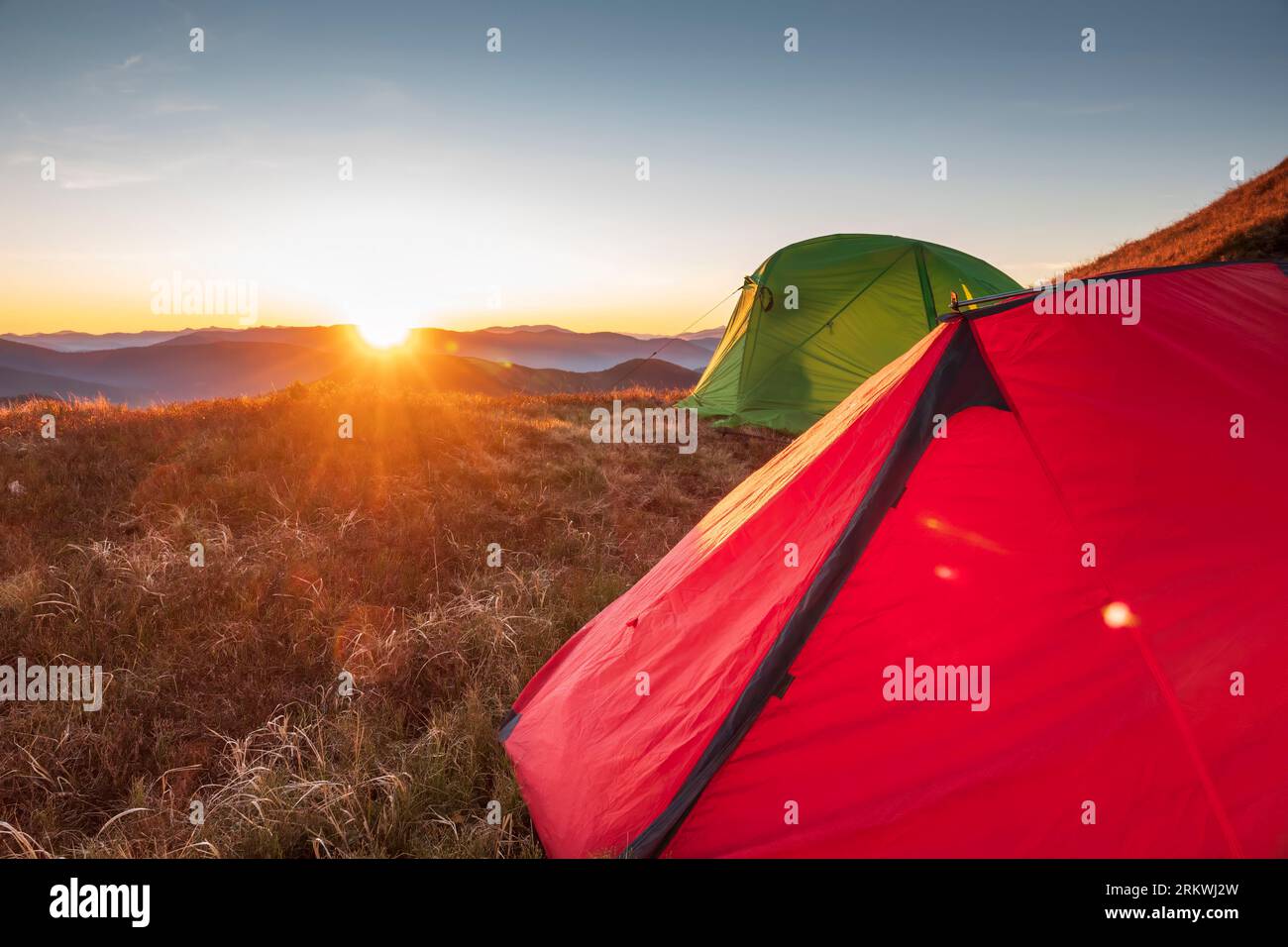 Tentes de randonnée colorées au coucher du soleil haut dans les montagnes. Vacances en plein air, exploration et mode de vie actif Banque D'Images