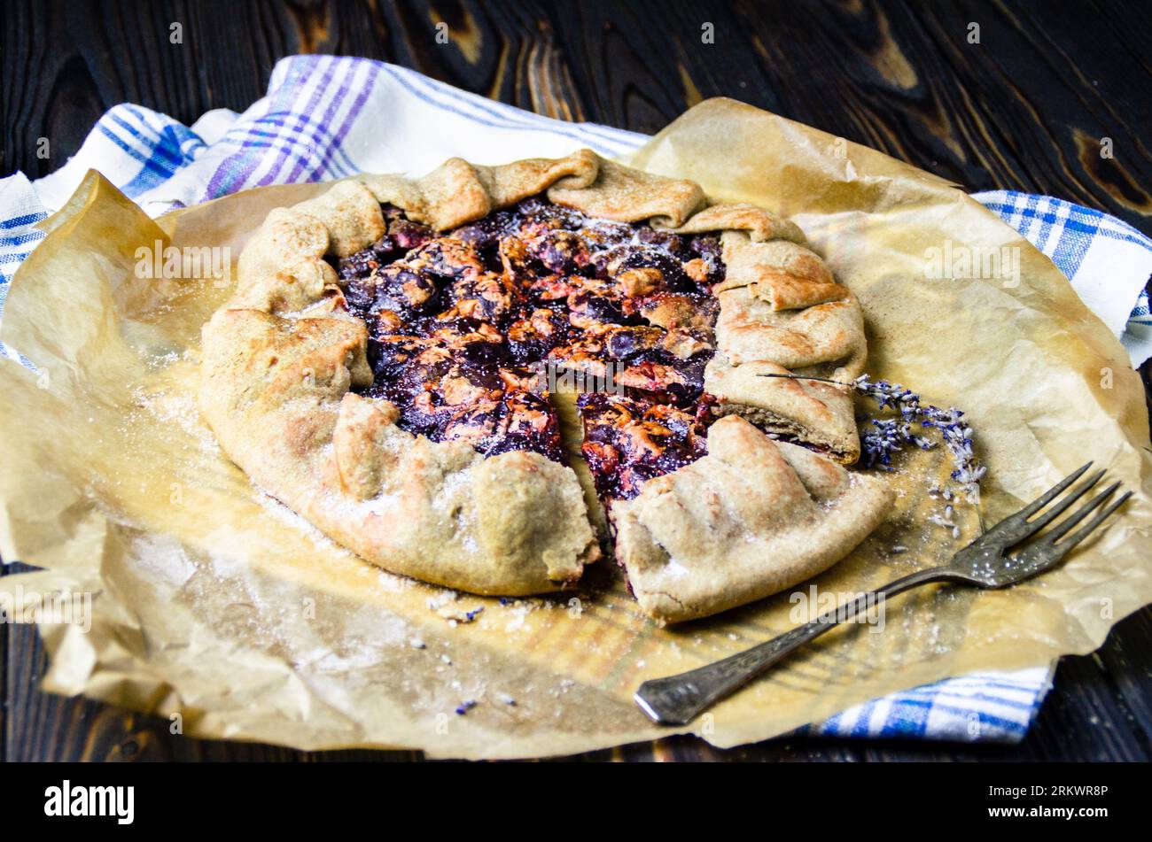 galette de fruits de prune crostata tarte sur le bureau en bois noir avec tissu de lin textile et ancienne fourchette en argent vintage. Photographie culinaire Banque D'Images