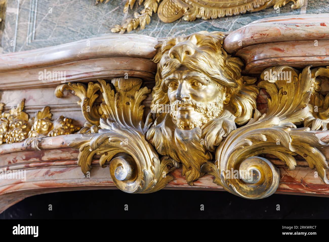Gros plan d'une gravure sur bois doré d'Hercule portant une crinière de lion montée sur une cheminée en marbre Banque D'Images