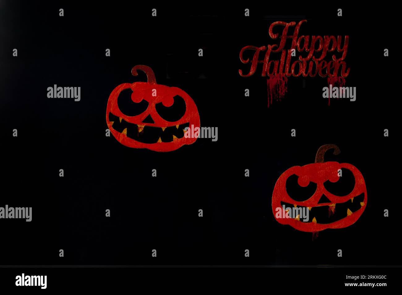 Visages de citrouille rouge grungy sur un fond noir. Banque D'Images