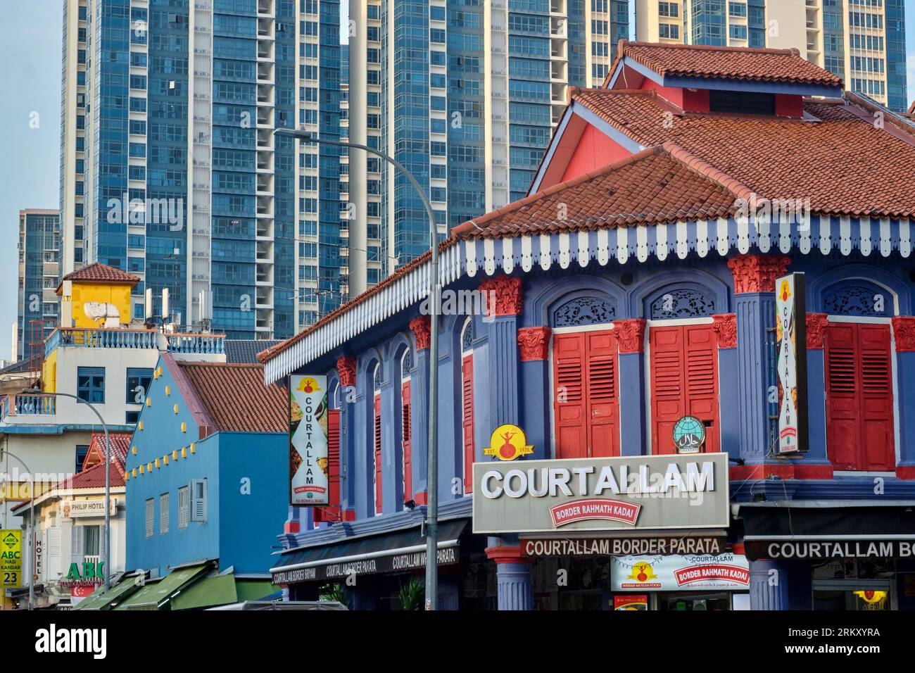 Un shophouse traditionnel coloré à Kampong Kapor Road, Little India, Singapour, avec un grand complexe résidentiel moderne en arrière-plan Banque D'Images