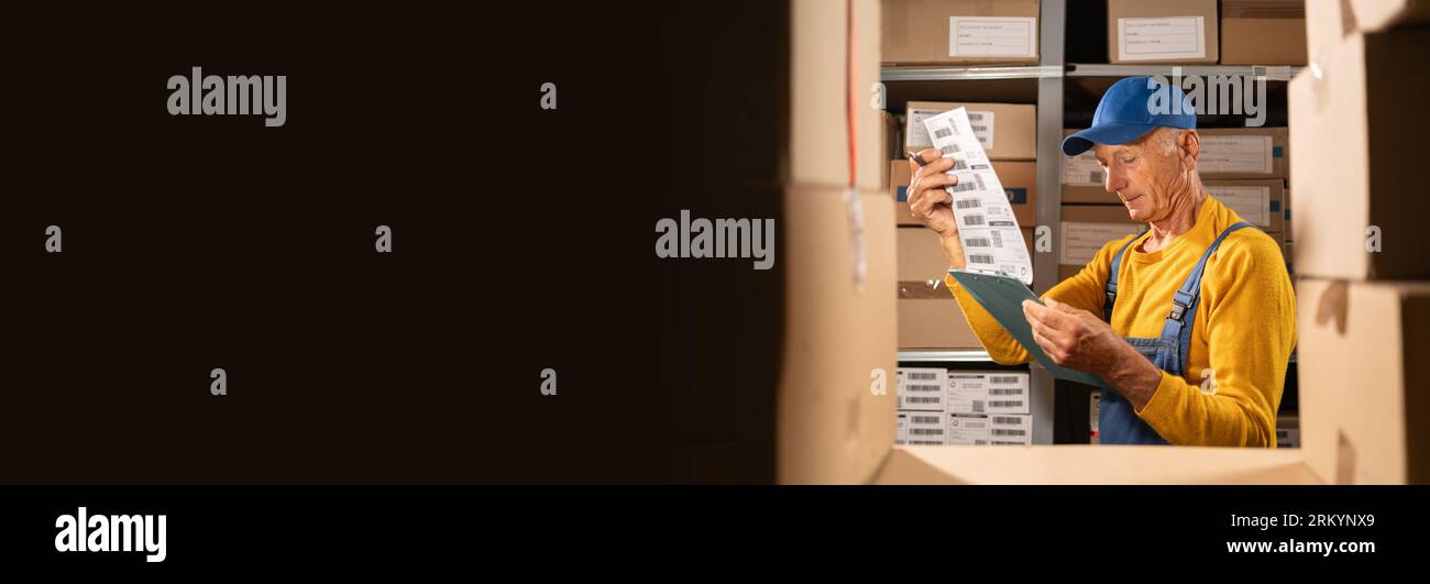 Travailleur masculin âgé avec presse-papiers dans l'entrepôt avec liste de contrôle vérifie l'inventaire Banque D'Images