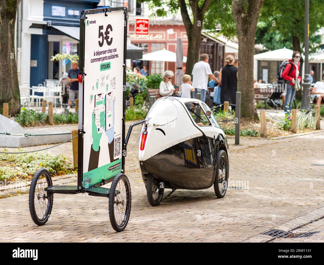 Publicité de remorquage de tricycle / capsule velomobile à propulsion humaine 'eCvelo' pour le système de paiement 'Retreeb' dans le centre-ville - Tours, Indre-et-Loire (37), France. Banque D'Images