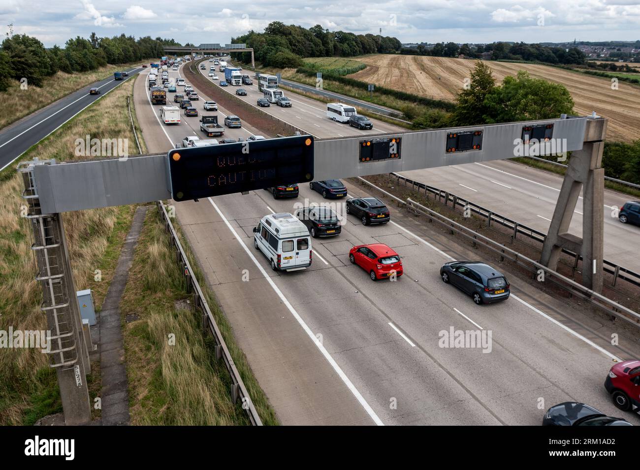 LEEDS, ROYAUME-UNI - 25 AOÛT 2023. Un panneau d'avertissement au-dessus d'une autoroute gérée par le Royaume-Uni avertissant les automobilistes de réduire leur vitesse et de prendre des précautions en raison d'un q Banque D'Images