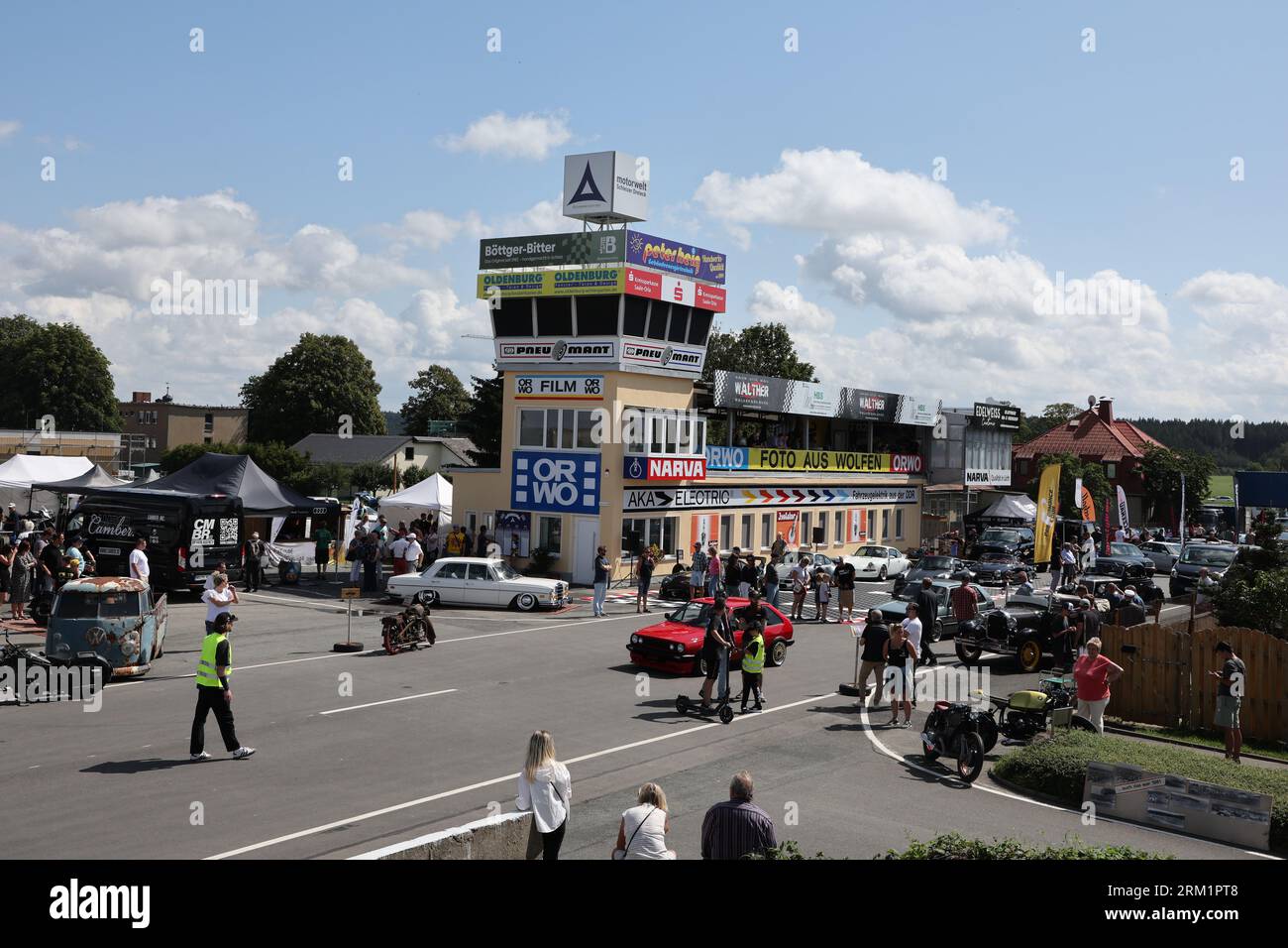 Schleiz, Allemagne. 26 août 2023. Les visiteurs traversent la zone d'exposition à l'ouverture du Motorwelt 'Schleizer Dreieck'. Le Schleizer Dreieck est le plus ancien circuit routier d'Allemagne et est encore aujourd'hui le lieu de courses dans les sports automobiles. Le musée sera consacré à l'histoire centenaire de l'hippodrome. Crédit : Bodo Schackow/dpa/Alamy Live News Banque D'Images