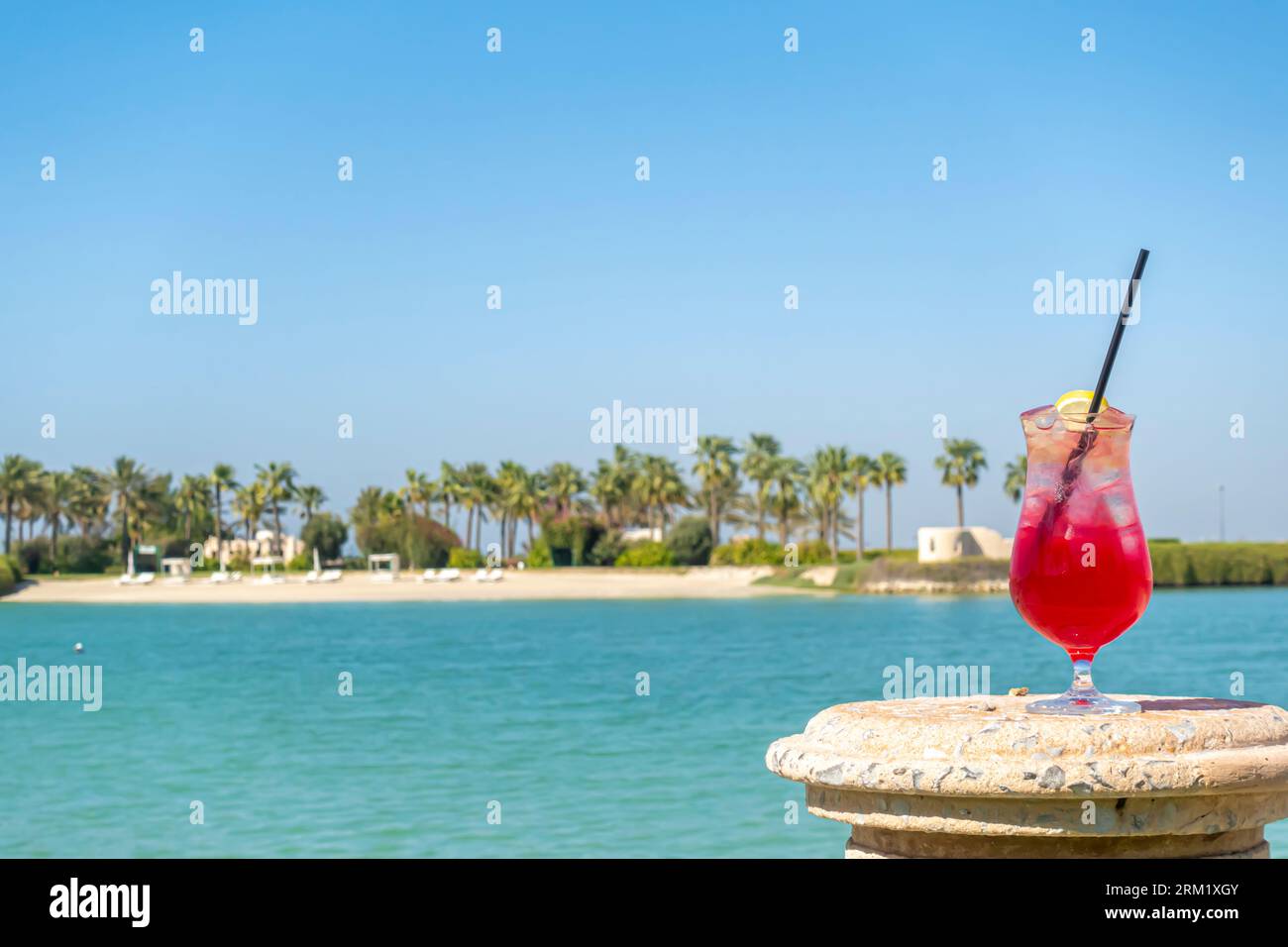 Verre de boisson rouge, limonade avec citron et paille contre la baie de Bahreïn, horizon du Moyen-Orient Banque D'Images