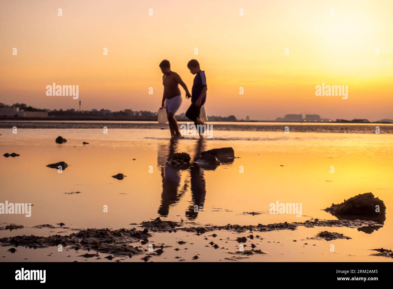 Deux garçons marchant avec de l'eau remplie dans des récipients en plastique, Banque D'Images
