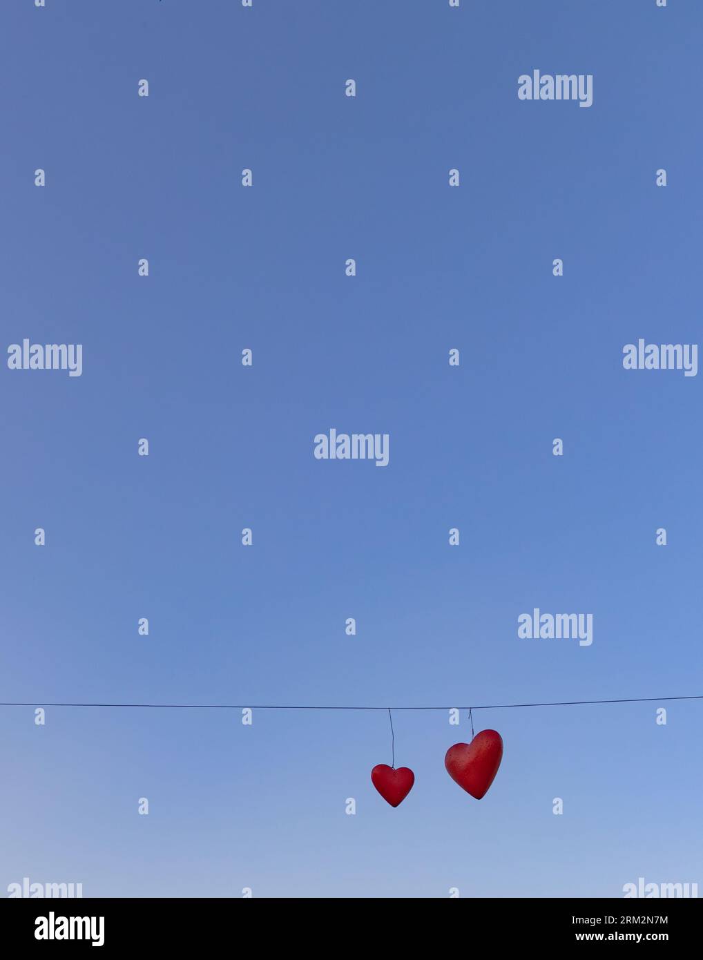 Deux coeurs sur une ficelle avec un ciel bleu en arrière-plan. L'amour est dans l'air Banque D'Images Deux coeurs sur une ficelle avec un ciel bleu en arrière-plan. L'amour est dans l'air Banque D'Images