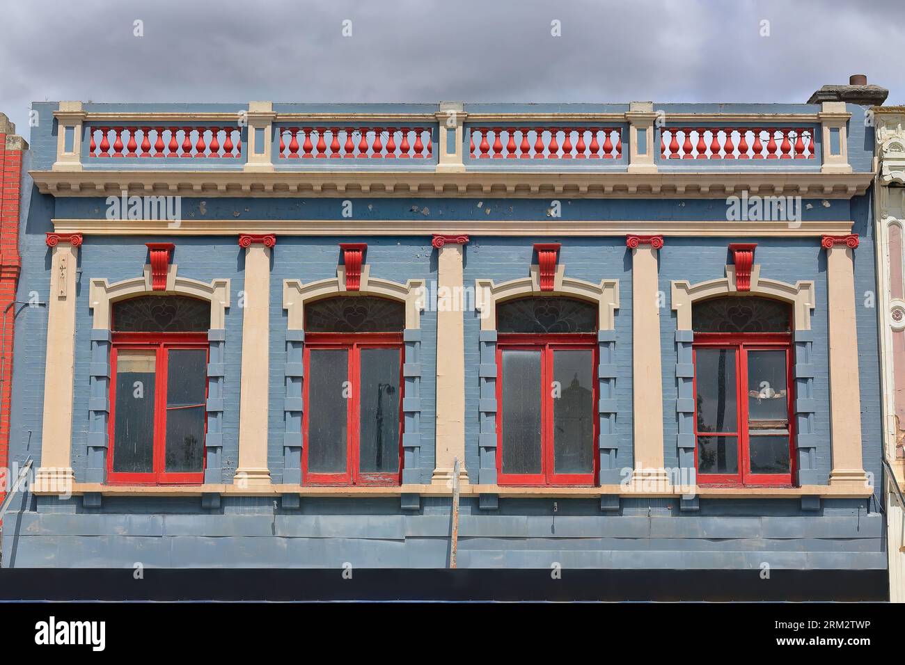 Façade de 877 de l'ancienne terrasse commerciale victorienne peinte bleu-rouge-crème avec parapet de balustrade, côté sud de Sturt Street. Ballarat-Australie. Banque D'Images