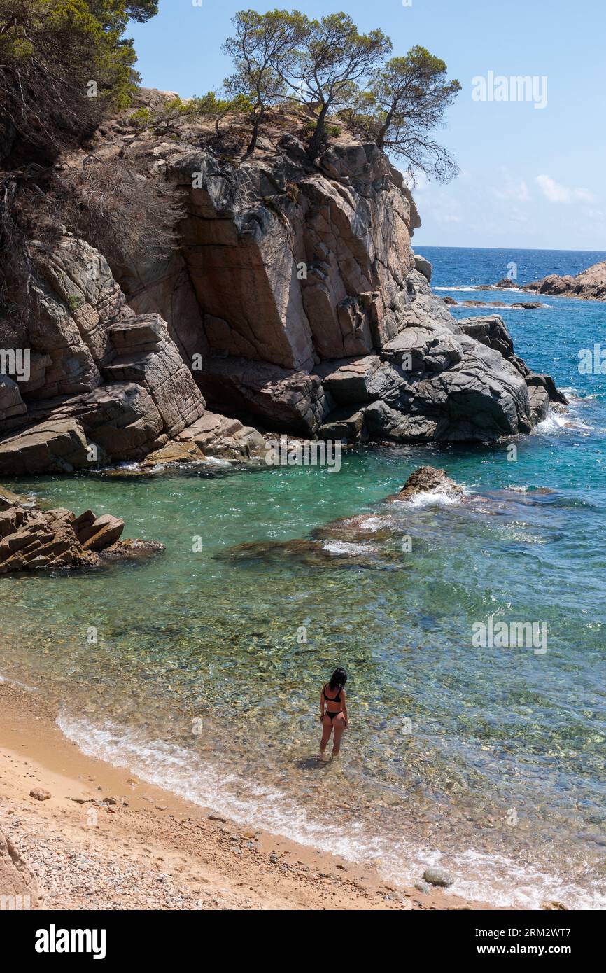 Femme solitaire appréciant des moments sereins sur une plage espagnole rocheuse Banque D'Images