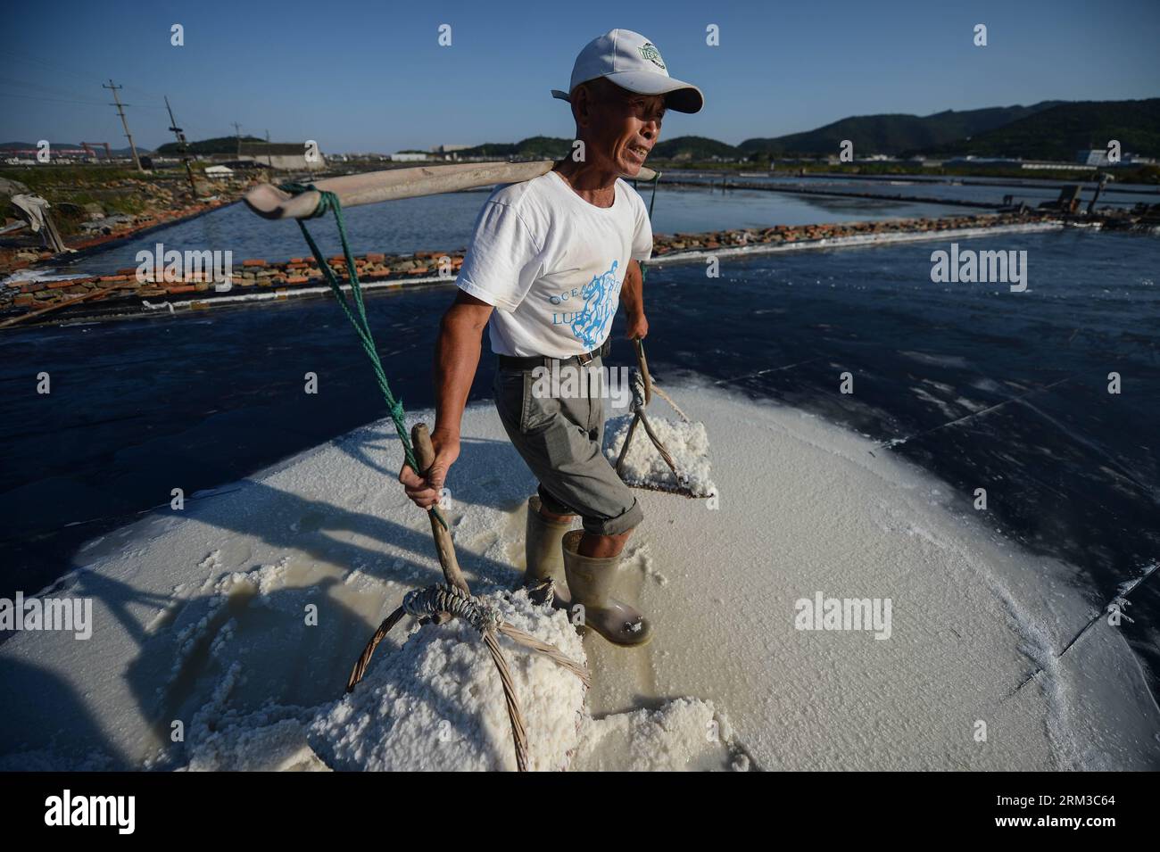 Bildnummer : 60136736 Datum : 16.07.2013 Copyright : imago/Xinhua (130716) -- DAISHAN, 16 juillet 2013 (Xinhua) -- soixante ans Shen Weiming transporte du sel dans le comté de Daishan, dans la province du Zhejiang de l'est de la Chine, 16 juillet 2013. La plupart des travailleurs dans le champ de sel ont plus de 60 ans. Daishan est le plus grand comté de production de sel dans le Zhejiang. Les travailleurs travaillent habituellement de longues heures au soleil pour évaporer la saumure pendant la période de production de sel doré de juillet à septembre, les trois mois les plus chauds de l'été. En raison du travail acharné et du faible revenu, moins de jeunes hommes aimeraient être engagés dans ce co Banque D'Images
