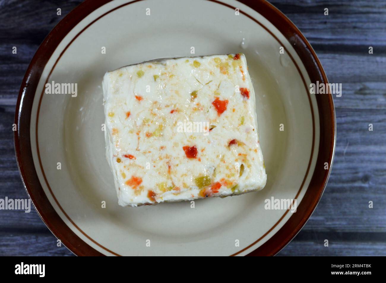 Une assiette avec un cube de baril égyptien Baramily fromage blanc avec des tranches de poivrons rouges et verts, un fromage traditionnel du Moyen-Orient à base de pasteur Banque D'Images