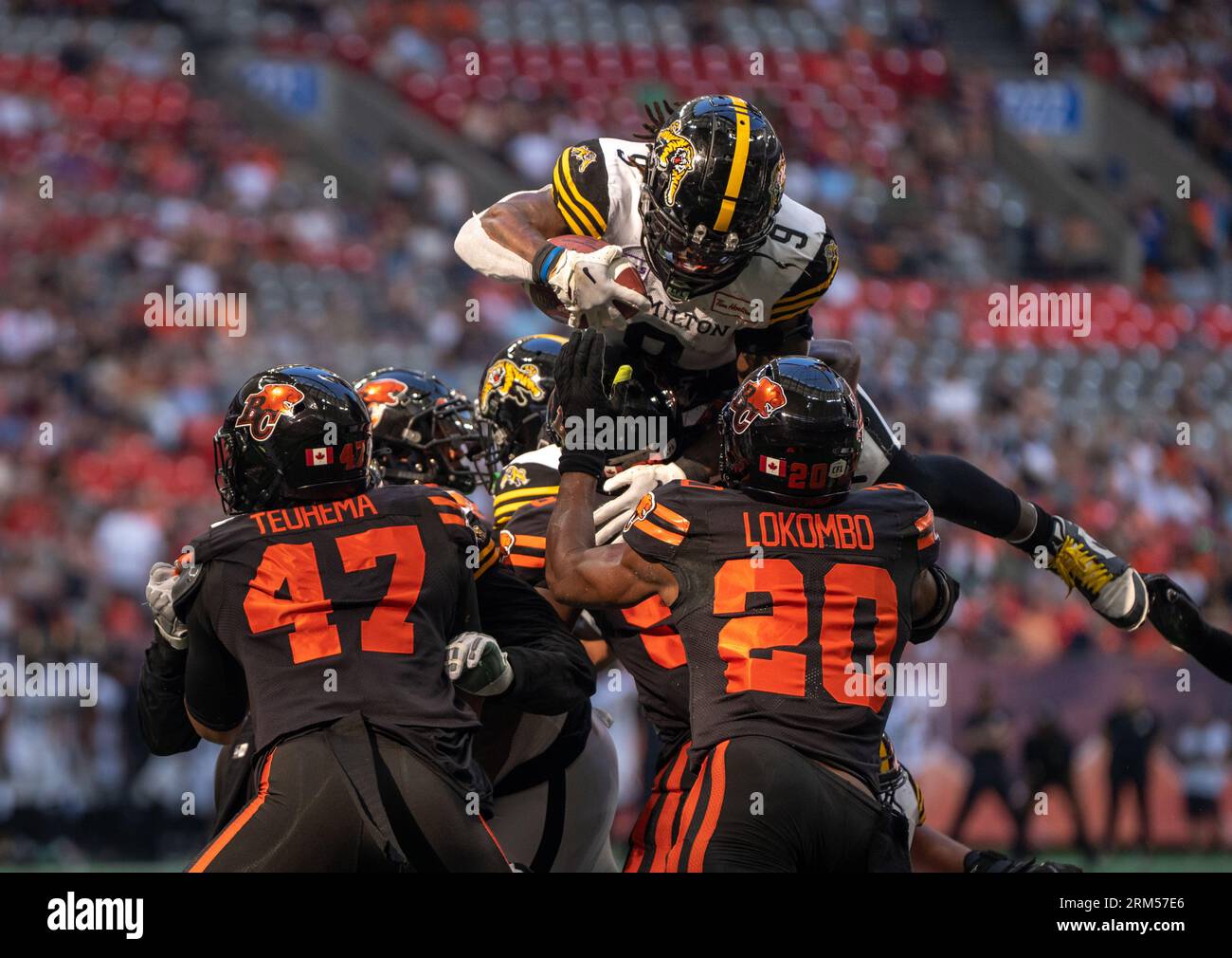 Vancouver, Canada. 26 août 2023. CORRIGE LE JOUEUR DE HAMILTON DANS VCRE102-103 -- James Butler des Tiger-Cats de Hamilton saute sur Sione Teuhema (47) et Boseko Lokombo (20) des Lions de la Colombie-Britannique pour marquer un touchdown lors de la première mi-temps de football de la LCF à Vancouver le samedi 26 août 2023. Crédit : la presse canadienne/Alamy Live News Banque D'Images