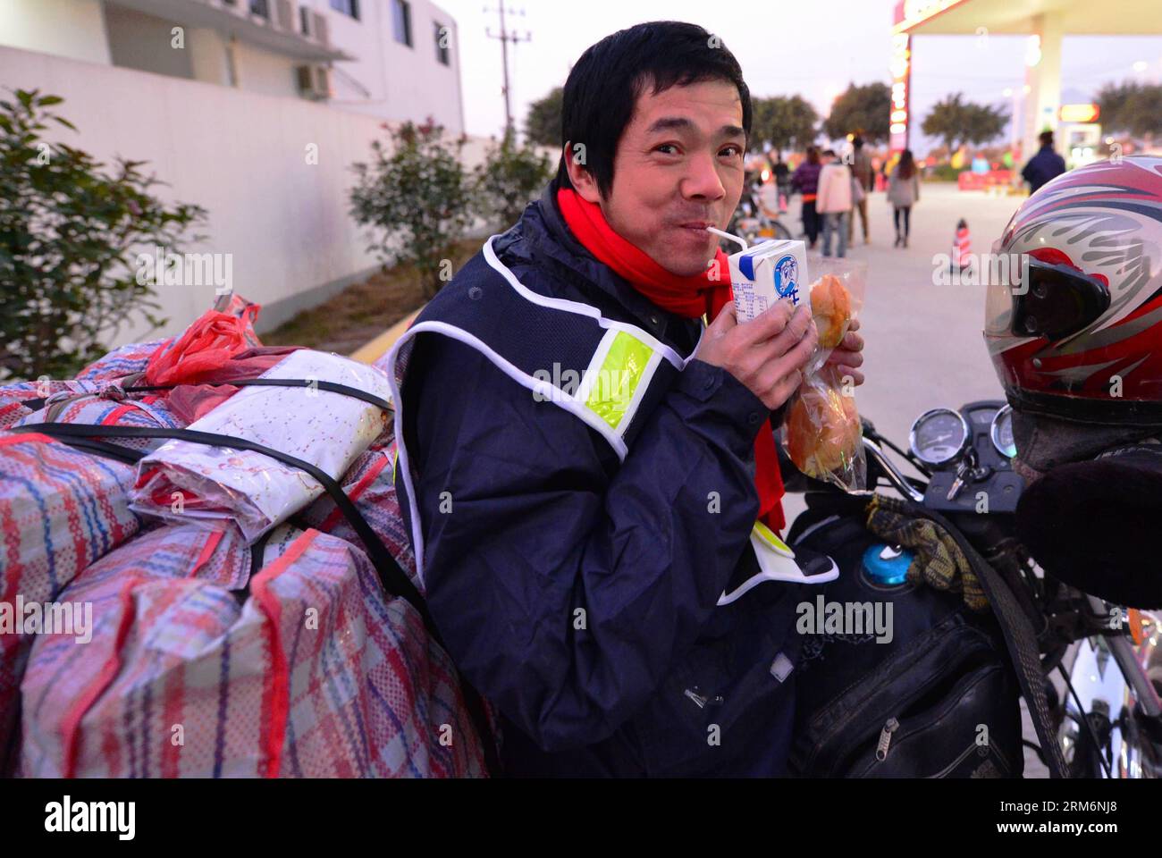 (140123) -- FUZHOU, 23 janv. 2014 (Xinhua) -- Un travailleur migrant prend son petit déjeuner avant de partir en moto depuis Fuzhou, capitale de la province du Fujian du sud-est de la Chine, le 23 janvier 2014. Plus de 1 500 travailleurs migrants au Fujian, dont la plupart des provinces du Jiangxi, de l’Anhui et du Hubei, ont commencé leur voyage en moto jeudi. En moyenne, les voyageurs en moto parcourront une distance de 700 kilomètres avant d’arriver dans leur pays d’origine pour une réunion de famille pendant le Festival du printemps, qui tombe le 31 janvier de cette année. (Xinhua/Wei Peiquan) (lmm) CHINE-TRAVAILLEUR MIGRANT Banque D'Images