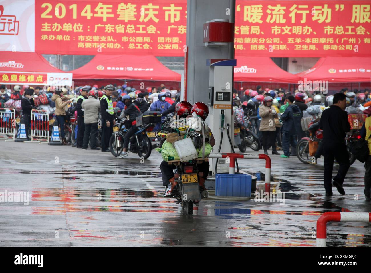 ZHAOQING, 24 janv. 2014 (Xinhua) -- deux travailleurs migrants qui font leur voyage à domicile en moto débarquent à un centre de services à Zhaoqing, dans la province du Guangdong, dans le sud de la Chine, le 24 janvier 2014. De nombreux travailleurs migrants du Guangdong sont originaires de la région autonome voisine de Guangxi Zhuang. Parmi eux, certains ont décidé de faire un voyage en moto de retour dans leur pays d’origine pour une réunion de famille pendant le Festival du printemps, qui tombe le 31 janvier cette année. À Zhaoqing, qui se trouve à la frontière entre Guangdong et Guangxi, 14 centres de services avec 15 000 bénévoles ont été mis en place pour offrir de l'aide au mot Banque D'Images