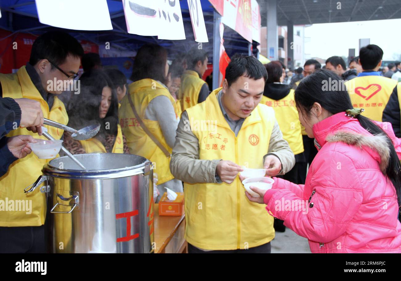 ZHAOQING, 24 janv. 2014 (Xinhua) -- Un bénévole offre de la bouillie de gingembre à un travailleur migrant à domicile qui fait le voyage en moto dans un centre de services à Zhaoqing, dans la province du Guangdong, dans le sud de la Chine, le 24 janvier 2014. De nombreux travailleurs migrants du Guangdong sont originaires de la région autonome voisine de Guangxi Zhuang. Parmi eux, certains ont décidé de faire un voyage en moto de retour dans leur pays d’origine pour une réunion de famille pendant le Festival du printemps, qui tombe le 31 janvier cette année. À Zhaoqing, qui se trouve à la frontière entre Guangdong et Guangxi, 14 centres de services avec 15 000 bénévoles ont été se Banque D'Images