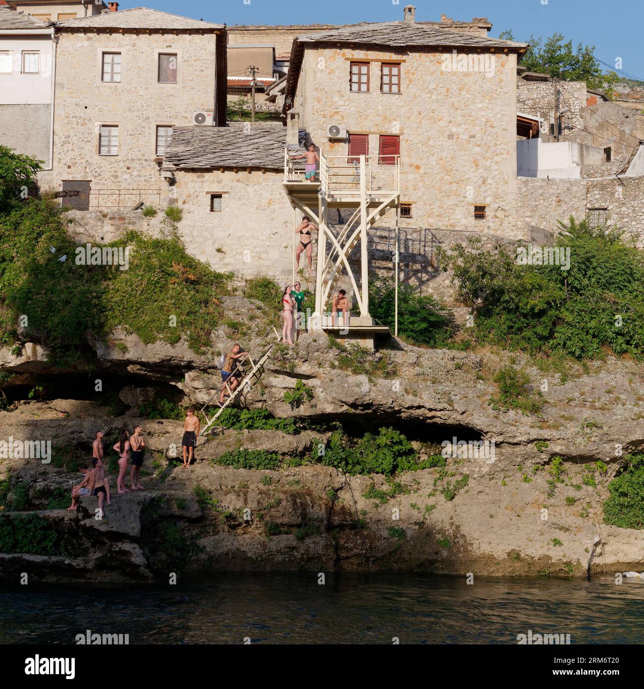 Des gens sautent d’une plate-forme d’entraînement à la plongée au-dessus de la rivière Neretva dans la ville de Mostar, Bosnie-Herzégovine, le 25 août 2023. Banque D'Images