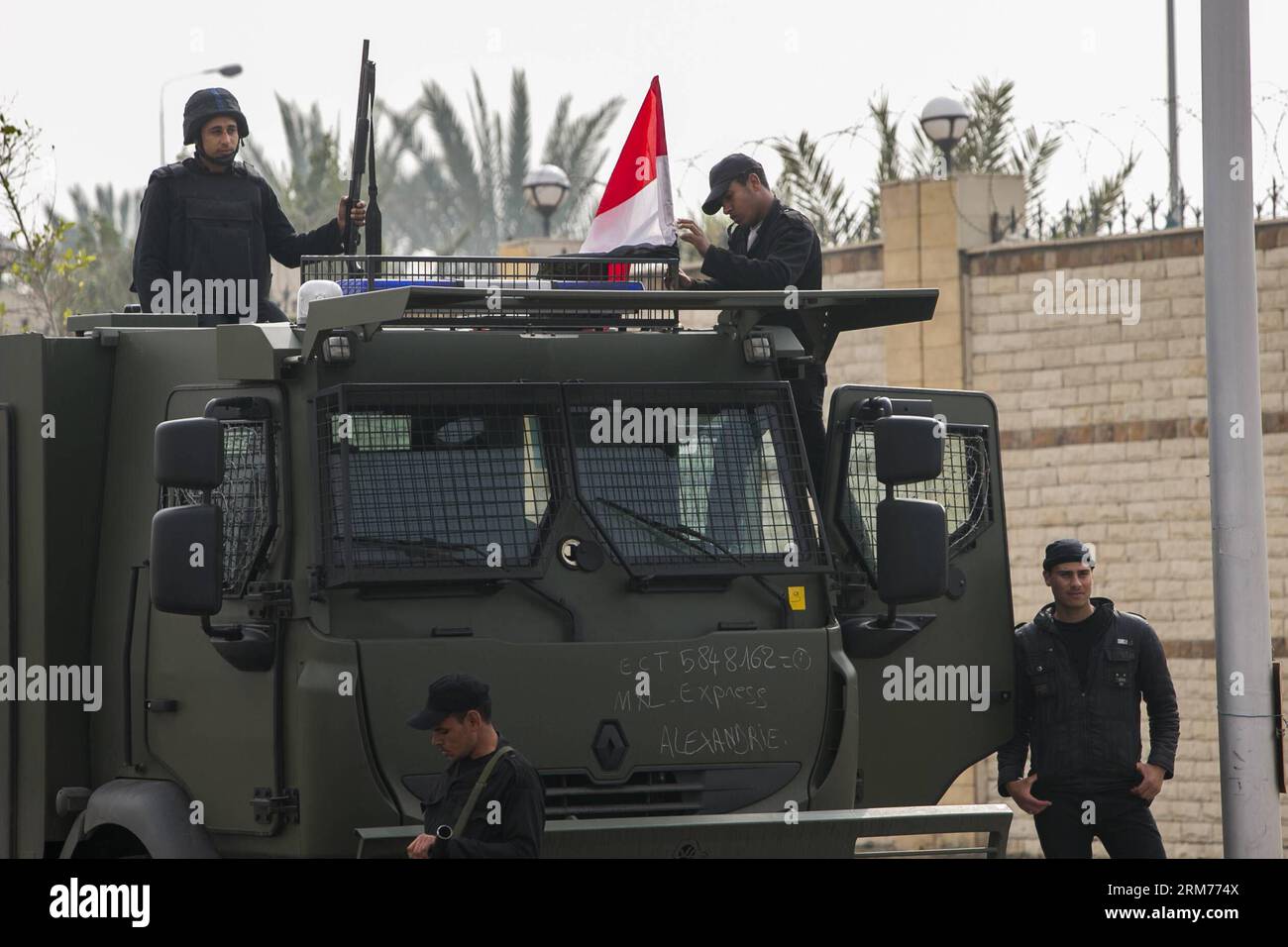 (140216) -- LE CAIRE, 16 février 2014 (Xinhua) -- Un policier pose un drapeau national sur un fourgon de police devant l'Académie de police du Caire au Caire, Égypte, le 16 février 2014. Un tribunal du Caire a ajourné dimanche le procès de l ancien président égyptien Mohamed Morsi pour des accusations d espionnage au 23 février, a rapporté l agence de presse officielle MENA. (Xinhua/Cui Xinyu) (djj) EGYPT-CAIRO-MORSI-TRIAL PUBLICATIONxNOTxINxCHN le Caire février 16 2014 XINHUA un policier pose un drapeau national sur un fourgon de police devant l'Académie de police du Caire au Caire Égypte février 16 2014 un tribunal du Caire a ajourné dimanche le procès de l'ancien Presi égyptien Banque D'Images
