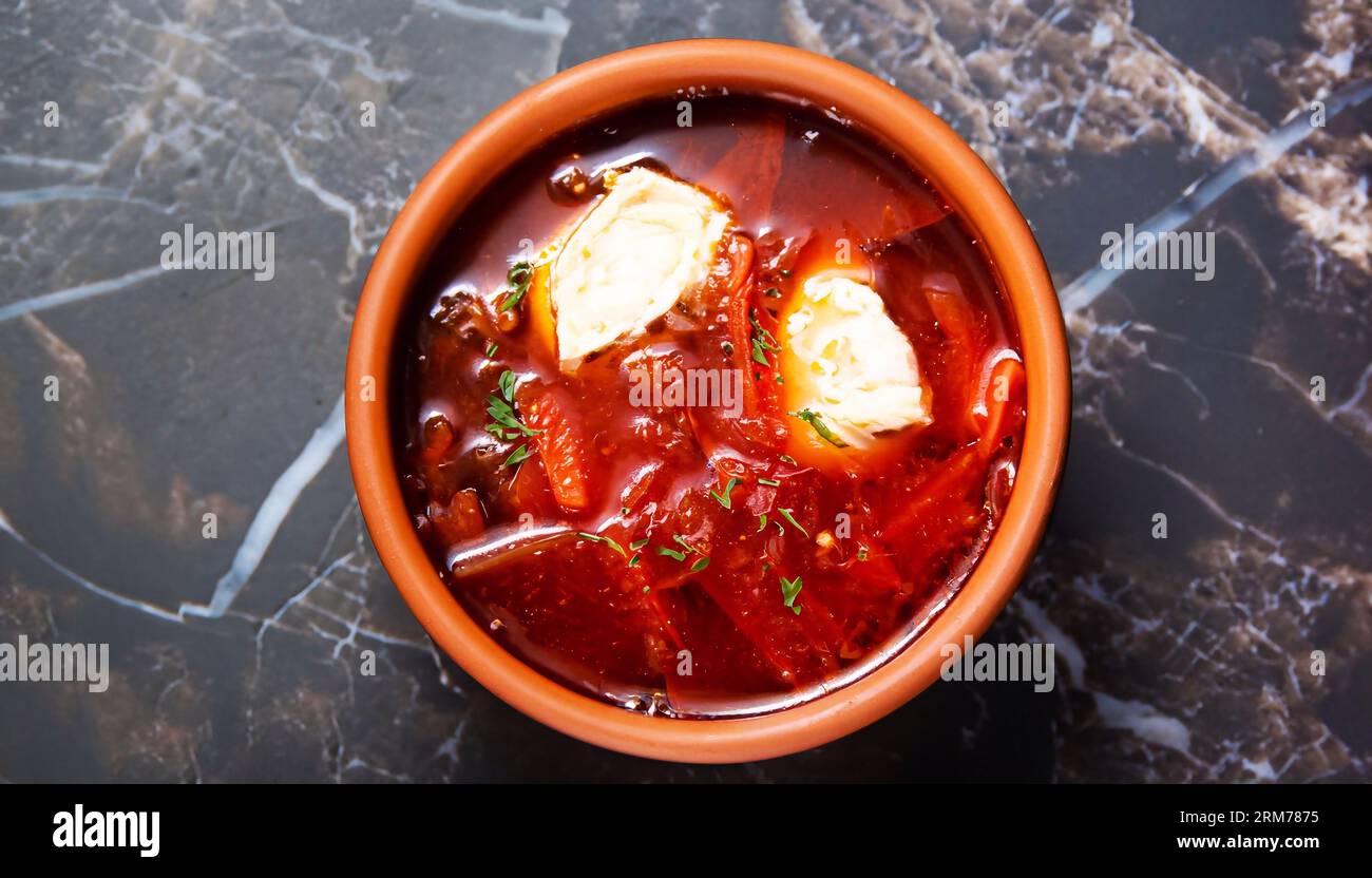 Soupe traditionnelle ukrainienne ou russe de légumes rouges et de viande Borscht dans des pots d'argile avec crème sure sur fond en bois. Vue de dessus. Banque D'Images