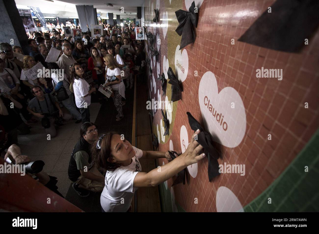 (140222) -- BUENOS AIRES, 22 février 2014 (Xinhua) -- Une personne en deuil met un ruban noir sur une carte nominative en forme de cœur lors de la cérémonie de commémoration de ceux qui ont été tués dans l'accident de train il y a deux ans, à Buenos Aires, Argentine, le 22 février 2014. 51 personnes ont été tuées et plus de 700 blessées lorsqu'un train de banlieue bondé a heurté les tampons de la gare à l'heure de pointe du matin le 22 février 2012 alors qu'il circulait sur la ligne de chemin de fer reliant la capitale Buenos Aires à sa banlieue ouest. (Xinhua/Martin Zabala) (zw) ARGENTINE-BUENOS AIRES-ANNIVERSAIRE DE L'ACCIDENT DE TRAIN PUBLICATIONxNOTxINxCHN Buenos Air Banque D'Images